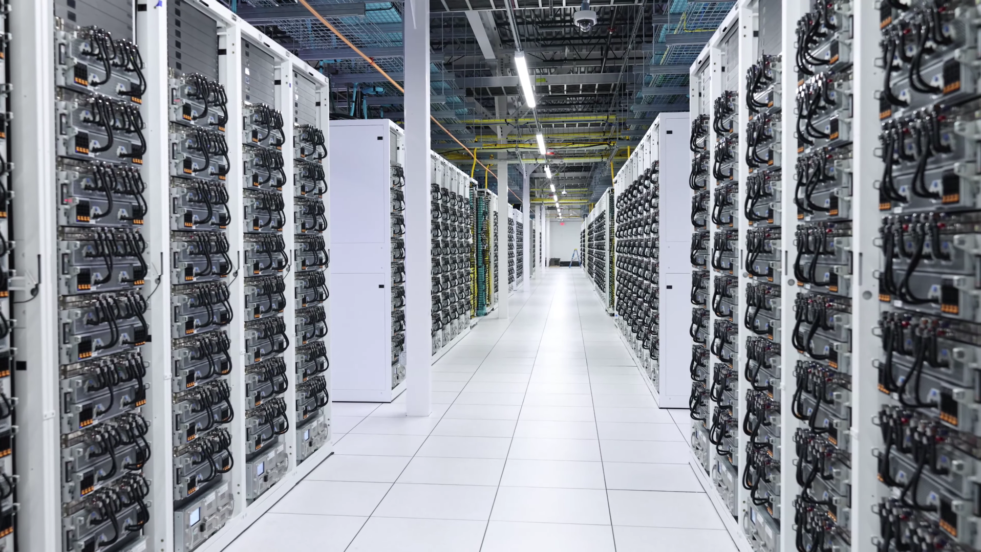 Image of xAI&amp;#039;s Colossus AI supercluster. Two rows of server racks continue into the distance.