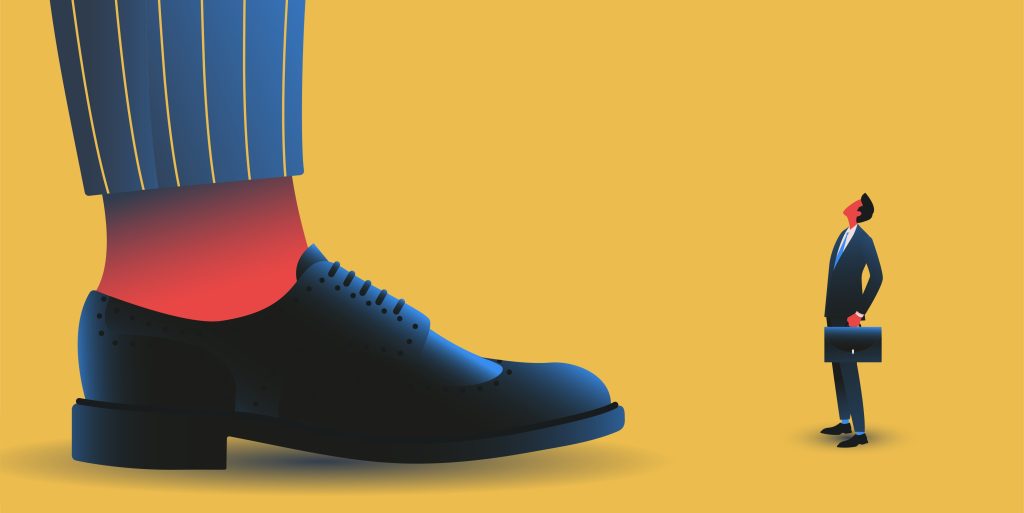 A tiny businessman in a suit faces an enormous dress shoe, illustrating the threat AI industry giants pose to startups trying to avoid being trampled by foundation model companies.