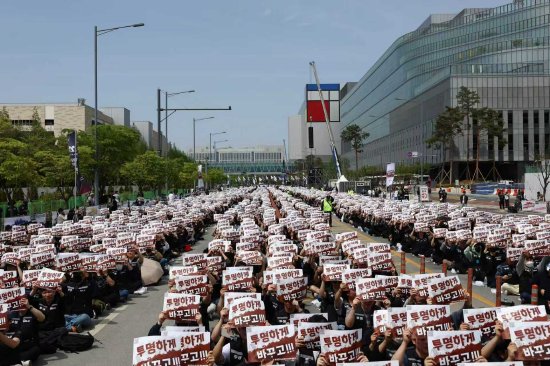 4月23日,在韩国平泽市三星电子半导体工厂外,三星电子员工在罢工前集会中举着标语牌。