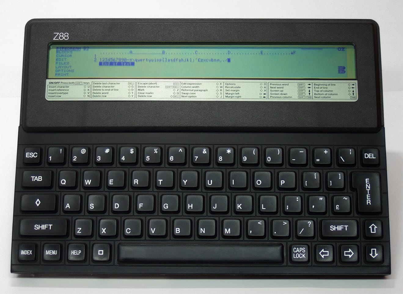 The Cambridge Z88, a flat slab of black, textured plastic with full keyboard and arrow keys. The screen at the top of the slab is 8 lines tall, 80 characters wide. PipeDream is running on it, showing text input and the familiar spreadsheet row/column identifiers. It